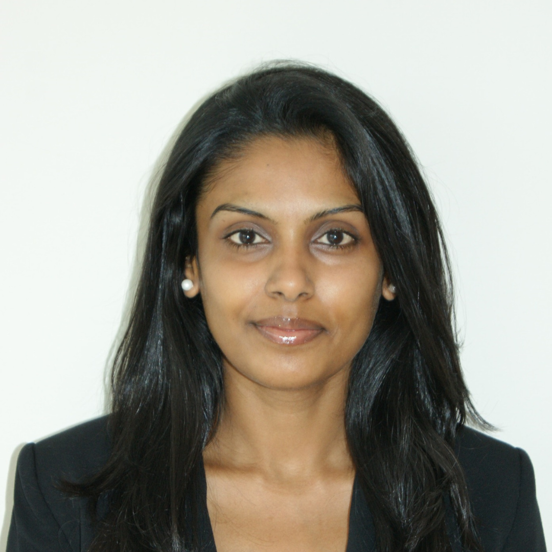 woman with dark hair and black suit jacket smiling at the camera