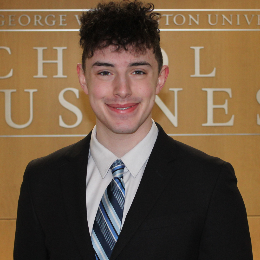 young man in black suit jacket and blue striped tie smiling at the camera
