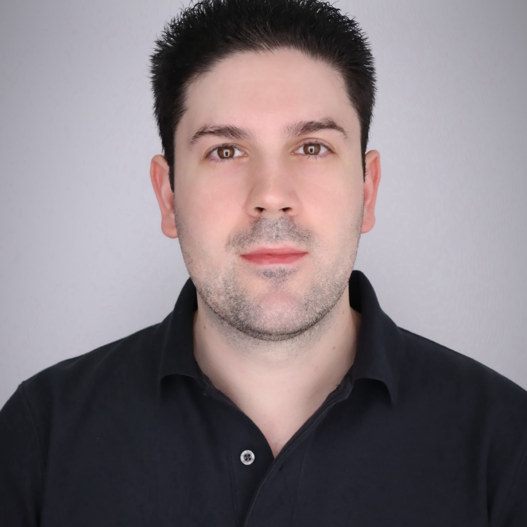 man with black collared shirt smiling at the camera
