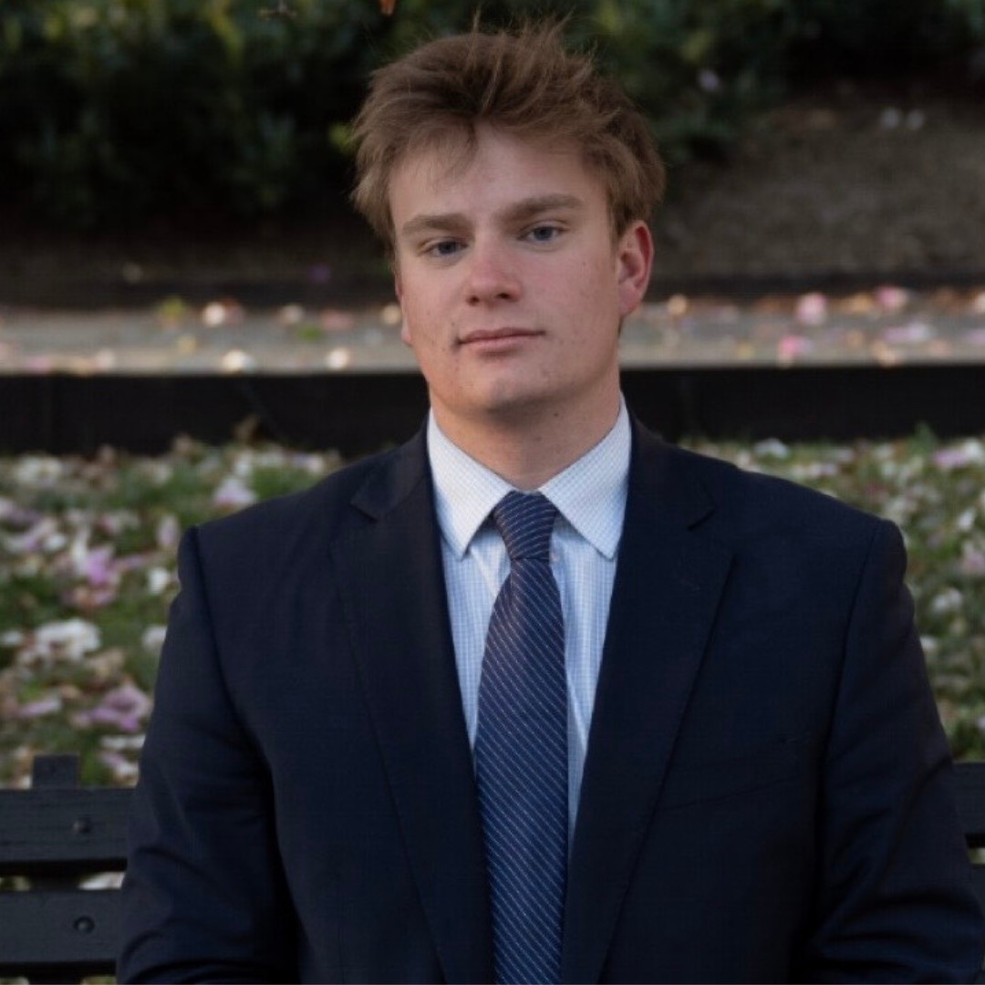 young man with black suit smiling at camera