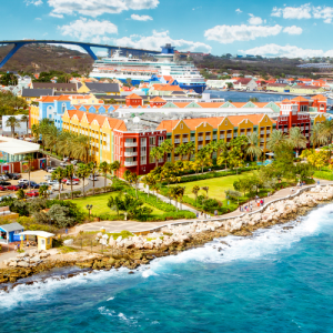 brightly colored hotel and buildings along the coast in curacao with a cruise ship in the background