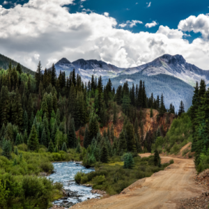 river running in the foreground of snowcapped mountains and pine trees