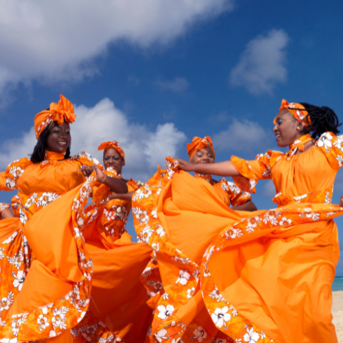 caribbean dancers in bright orange dresses with white flowers