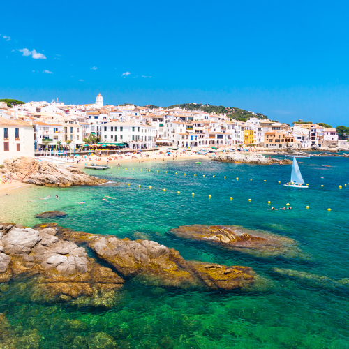 coastal community along blue green water with sail boat in the water