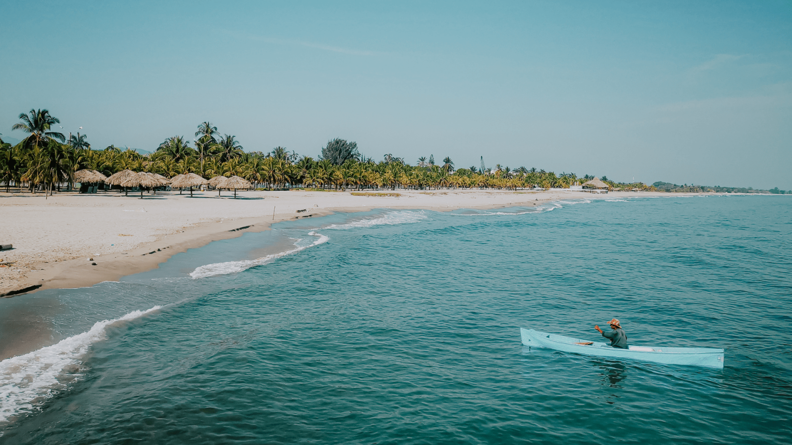 man in blue canoe near shoreline along beach